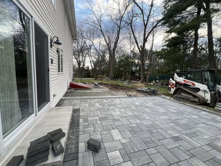 Residential patio and driveway area paved with interlocking concrete pavers, showcasing a popular paving material option for homeowners.