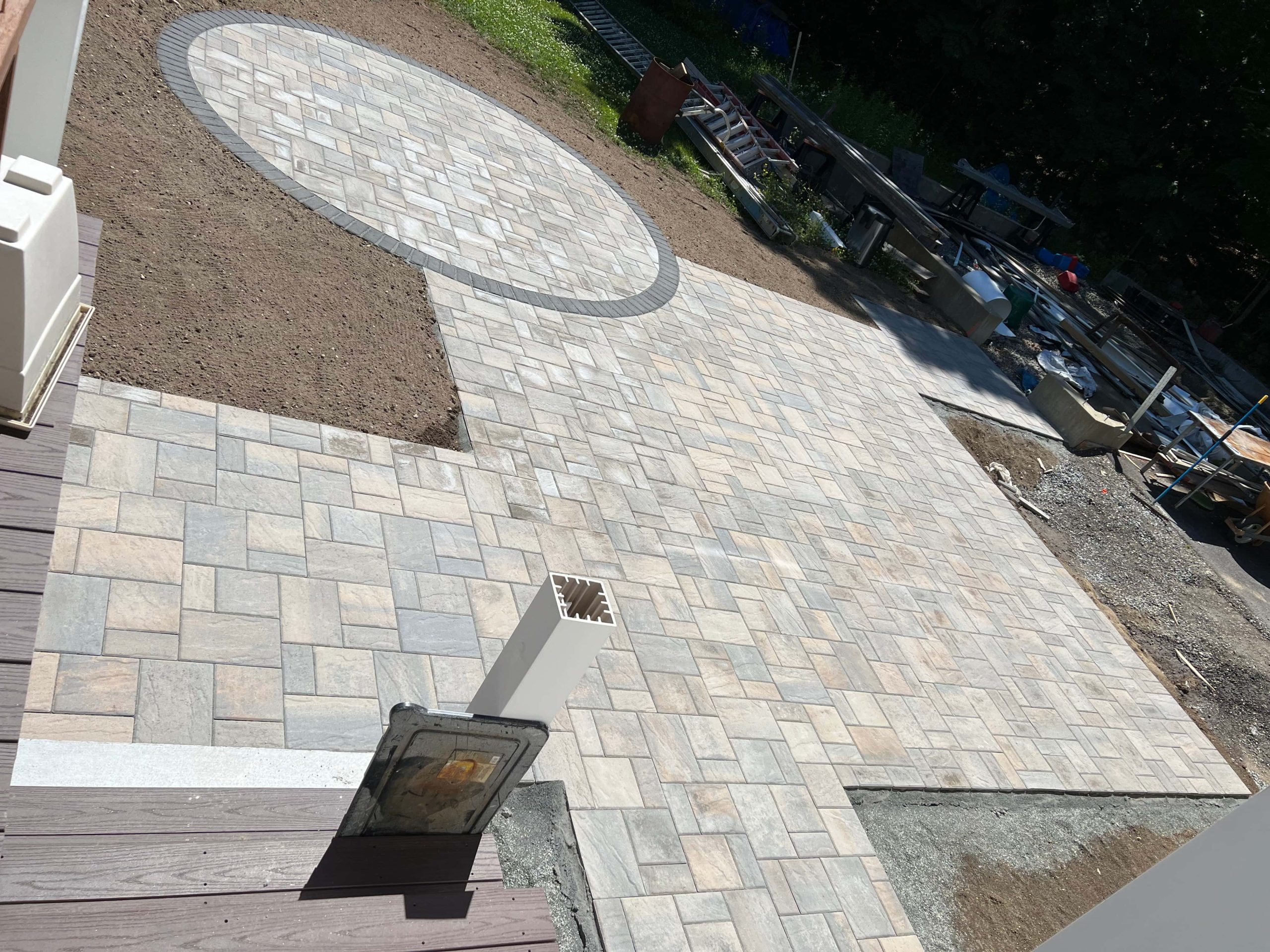 Custom interlocking paver patio with a circular gathering area and contrasting border installed by MDZ Crew Landscaping
