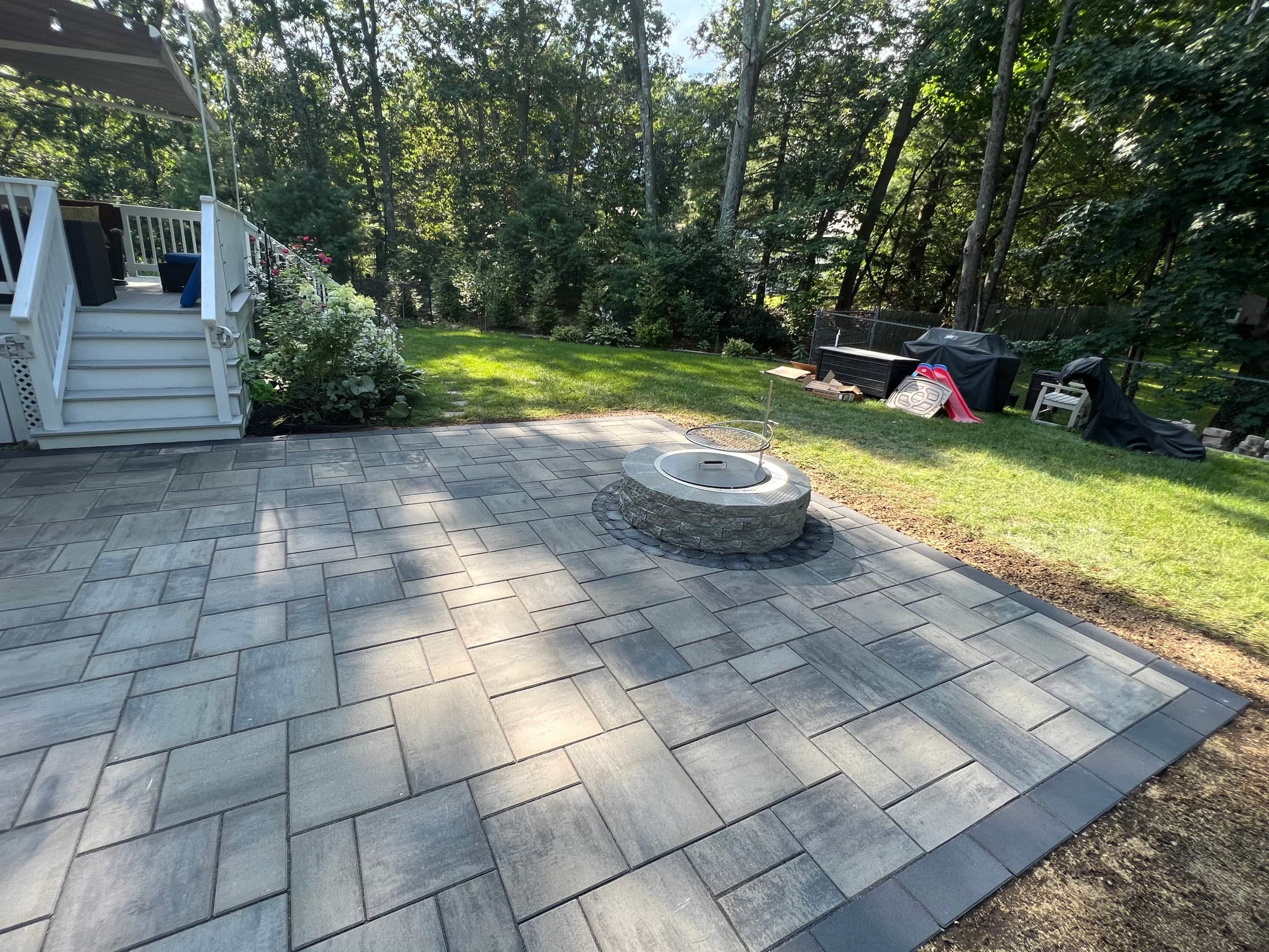 Custom paver patio with fire pit and modern backyard hardscape by MDZ Crew Landscaping & Paving Inc.