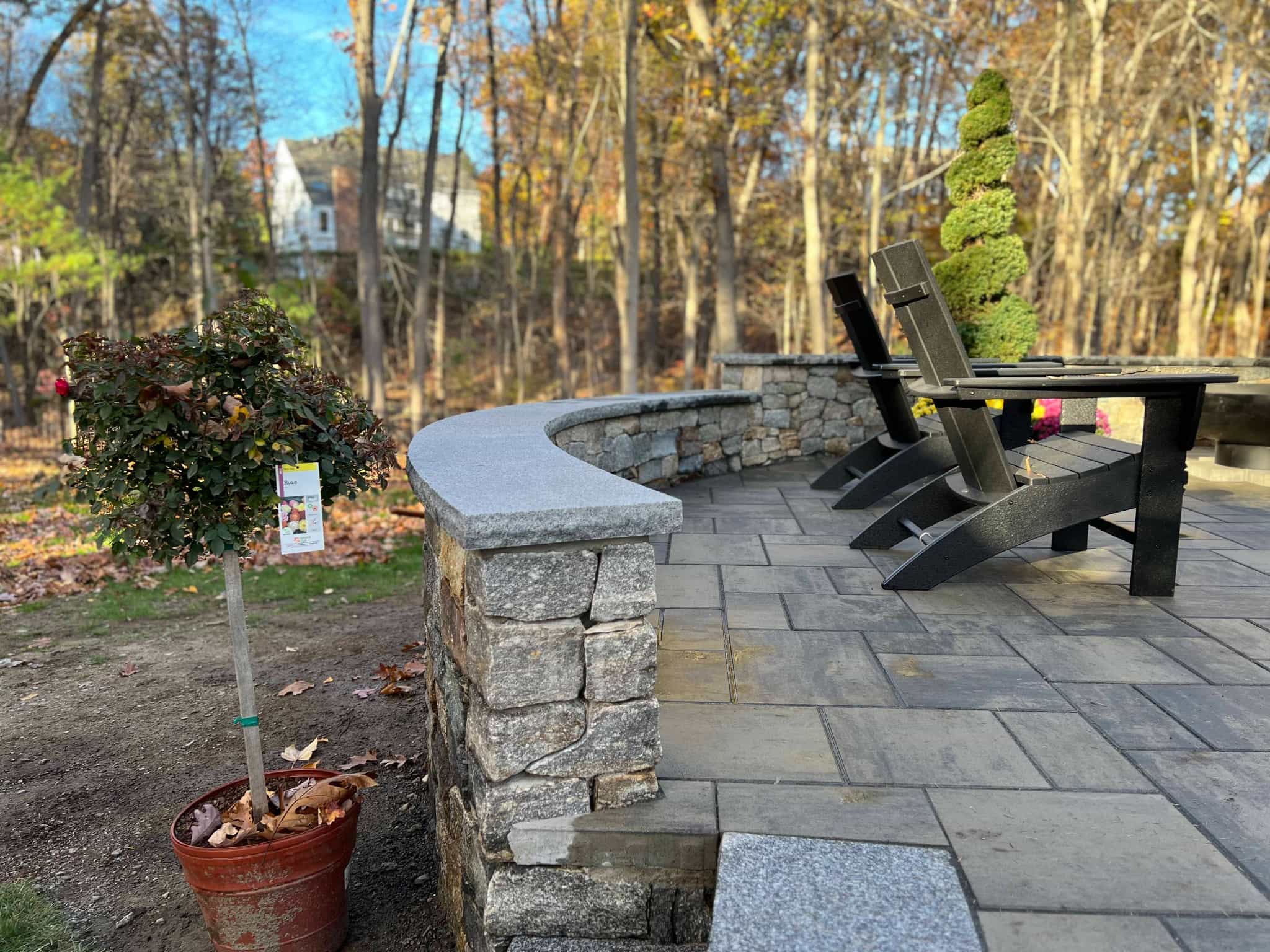 Custom stone patio with curved seating wall, granite caps, and outdoor dining area by MDZ Crew Landscaping & Paving Inc.