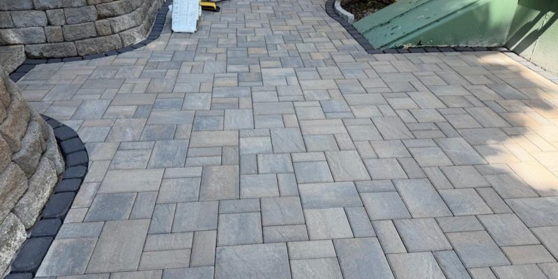 New permeable interlocking paver patio installation with decorative border and retaining wall by MDZ Crew Landscaping & Paving Inc.