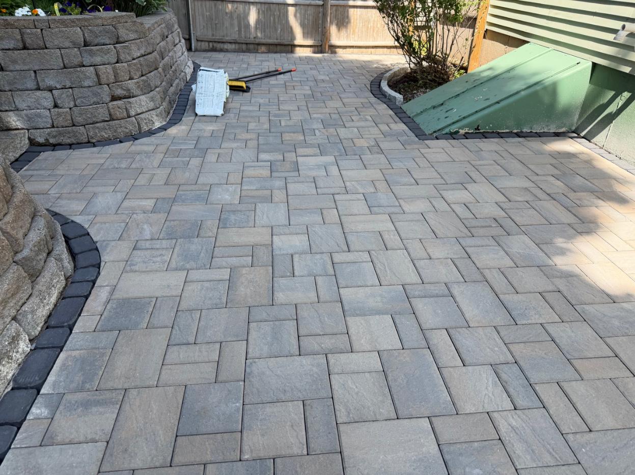 New permeable interlocking paver patio installation with decorative border and retaining wall by MDZ Crew Landscaping & Paving Inc.