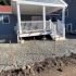 Paver patio base preparation with compacted stone aggregate around a residential porch